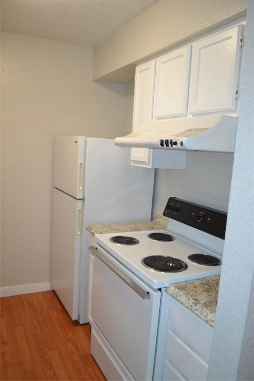 701 West Sycamore Street, Unit 207 Denton, TX 76201 - Photo 6 of 10 Kitchen featuring fridge, stove, exhaust hood, white cabinets, and hardwood / wood-style flooring