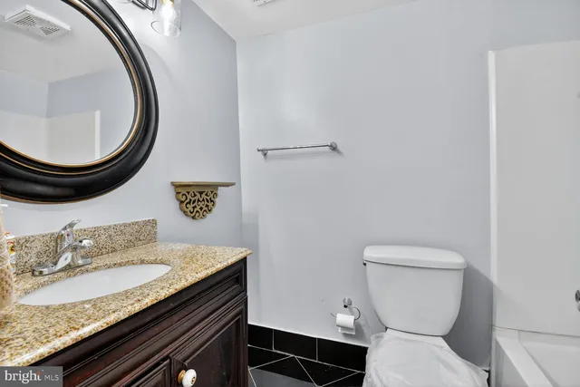 a bathroom with a granite countertop toilet and a sink