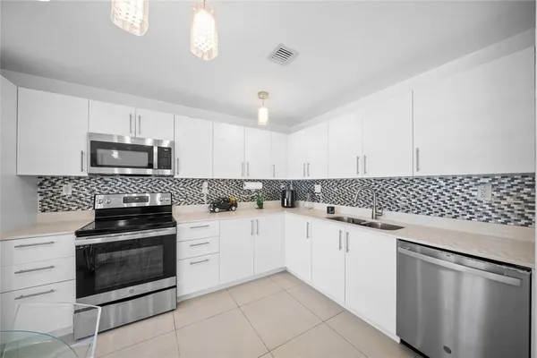 a kitchen with granite countertop white cabinets and stainless steel appliances