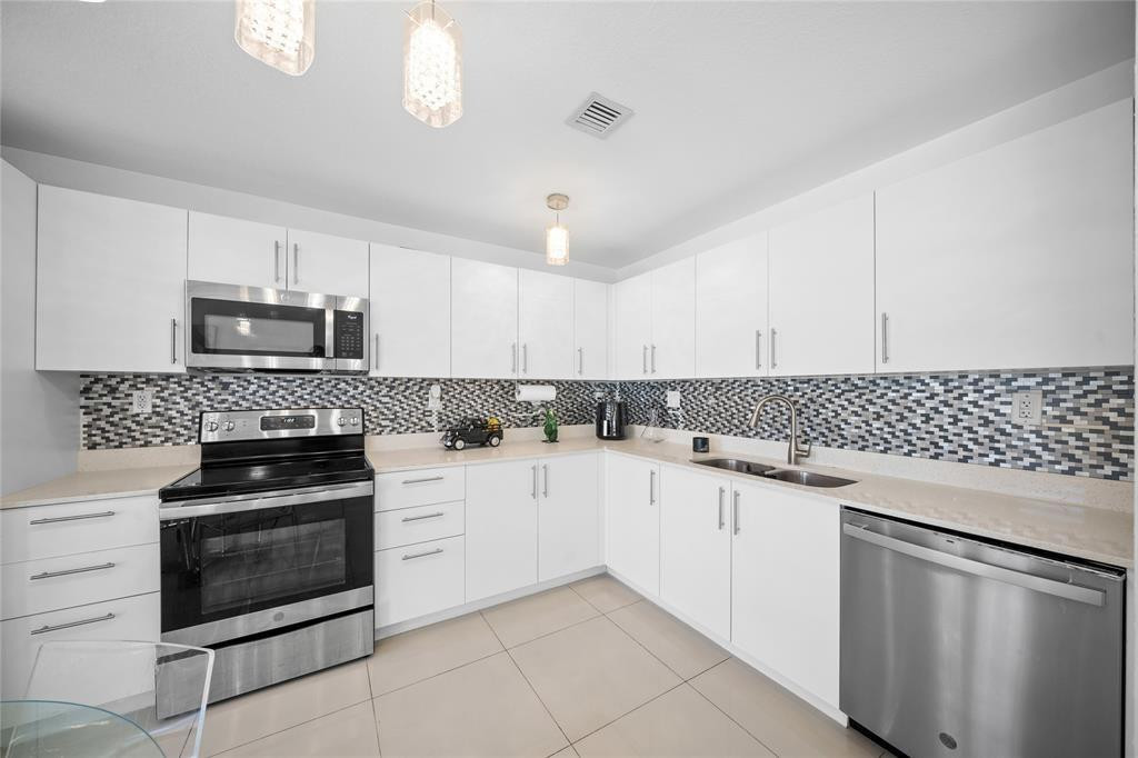 14474 Southwest 259th Street Homestead, FL 33032 - Photo 4 of 25 a kitchen with granite countertop white cabinets and stainless steel appliances