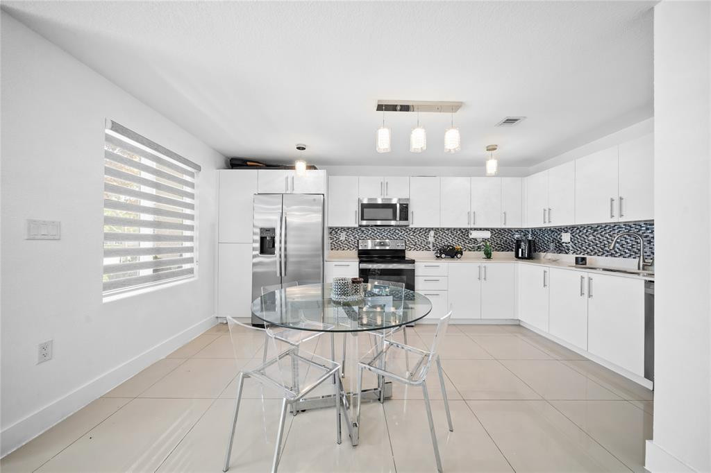 14474 Southwest 259th Street Homestead, FL 33032 - Photo 7 of 25 a kitchen with stainless steel appliances kitchen island granite countertop a stove a sink and a microwave