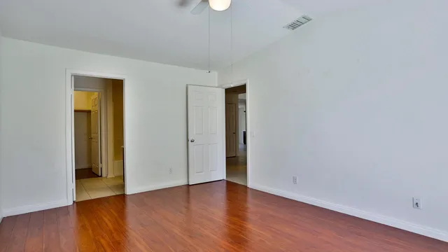 a view of an empty room with wooden floor and closet