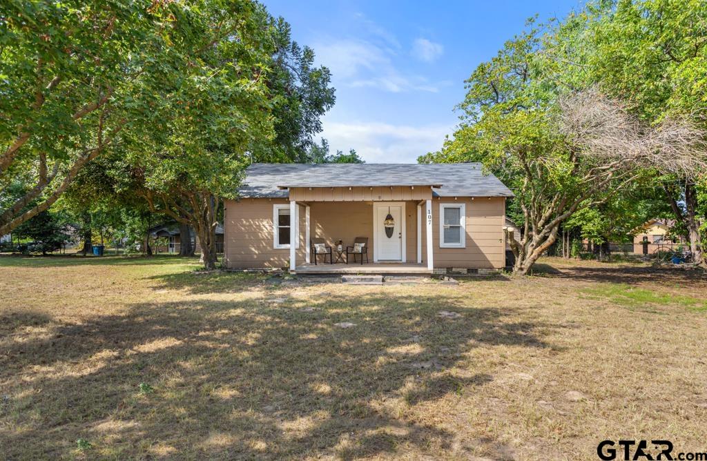 a view of a house with a yard and large tree
