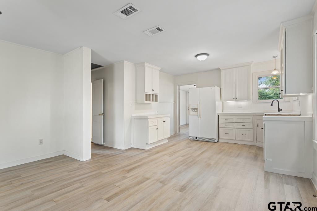 107 Mallory Street Lindale, TX 75771 - Photo 18 of 33 a view of a kitchen with white cabinets and wooden floor