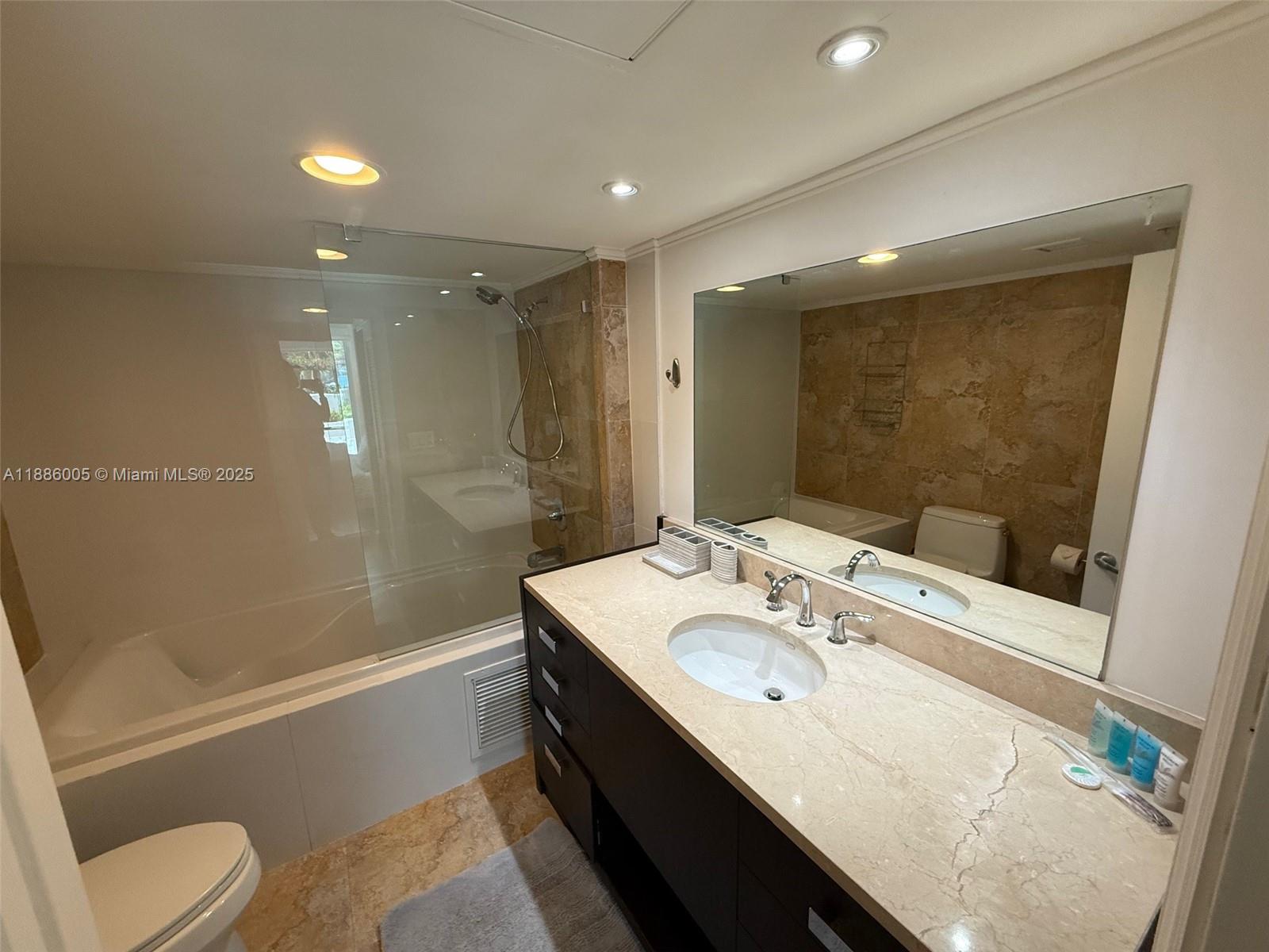 1500 Bay Road, Unit 122S Miami Beach, FL 33139 - Photo 17 of 44 a bathroom with a granite countertop sink a toilet a mirror and shower