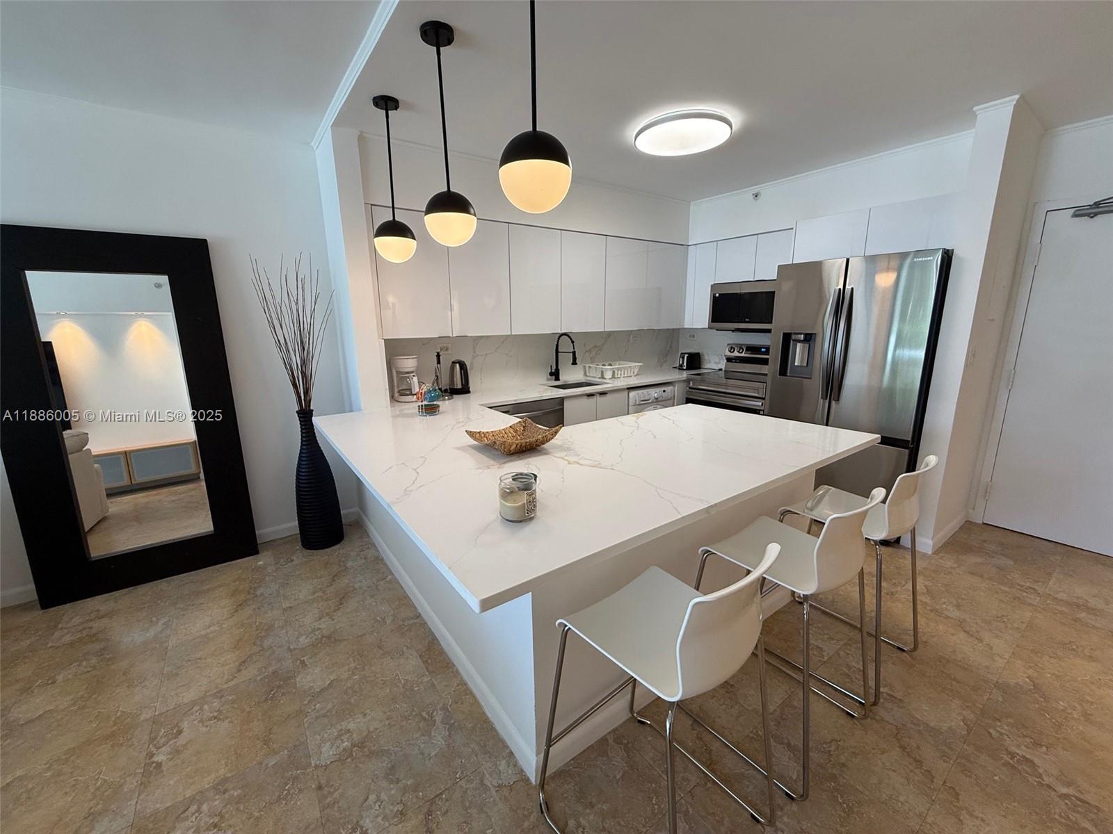 1500 Bay Road, Unit 122S Miami Beach, FL 33139 - Photo 7 of 44 a kitchen with stainless steel appliances a table chairs and a refrigerator