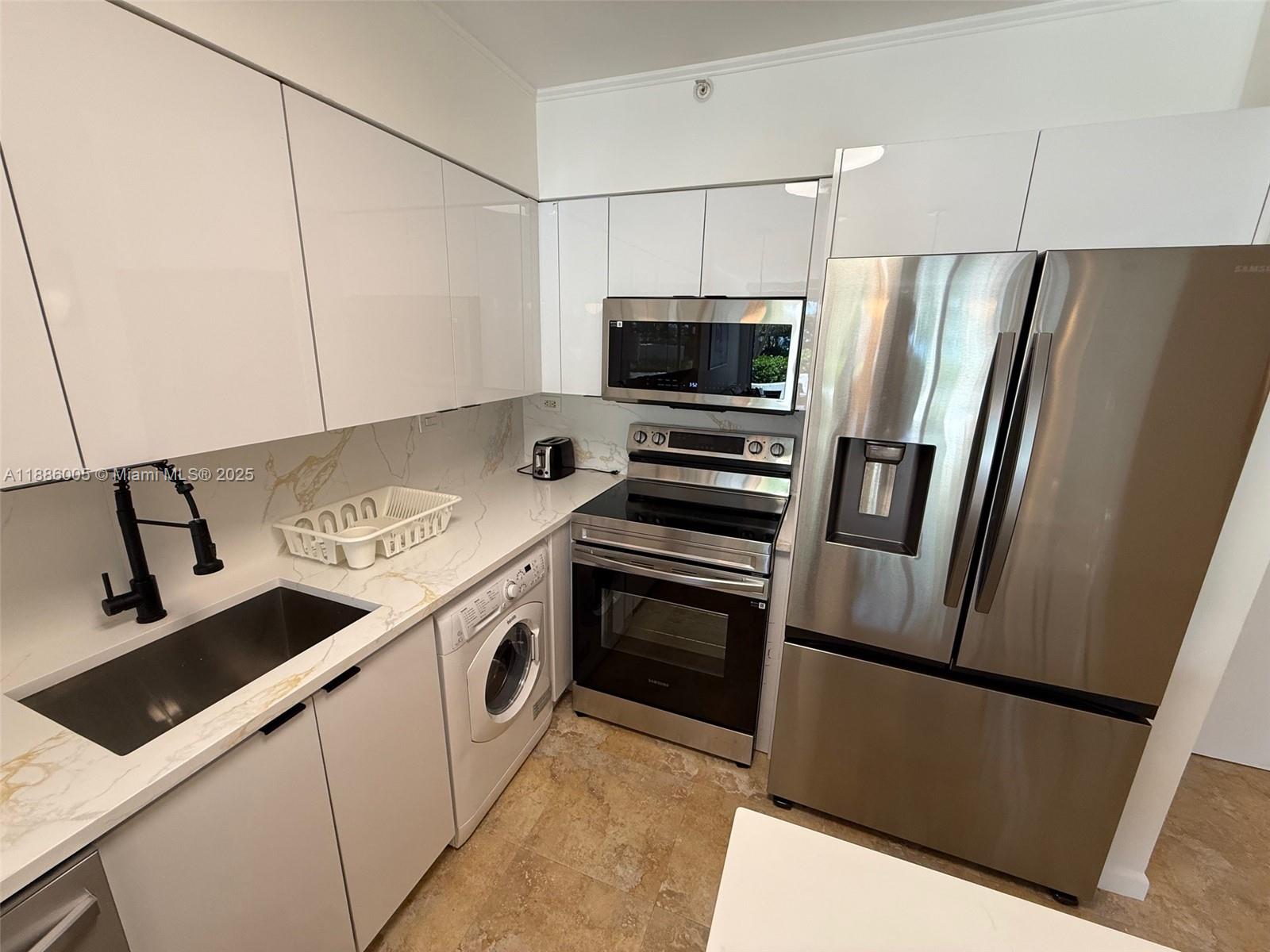 1500 Bay Road, Unit 122S Miami Beach, FL 33139 - Photo 9 of 44 a kitchen with stainless steel appliances a refrigerator sink and microwave