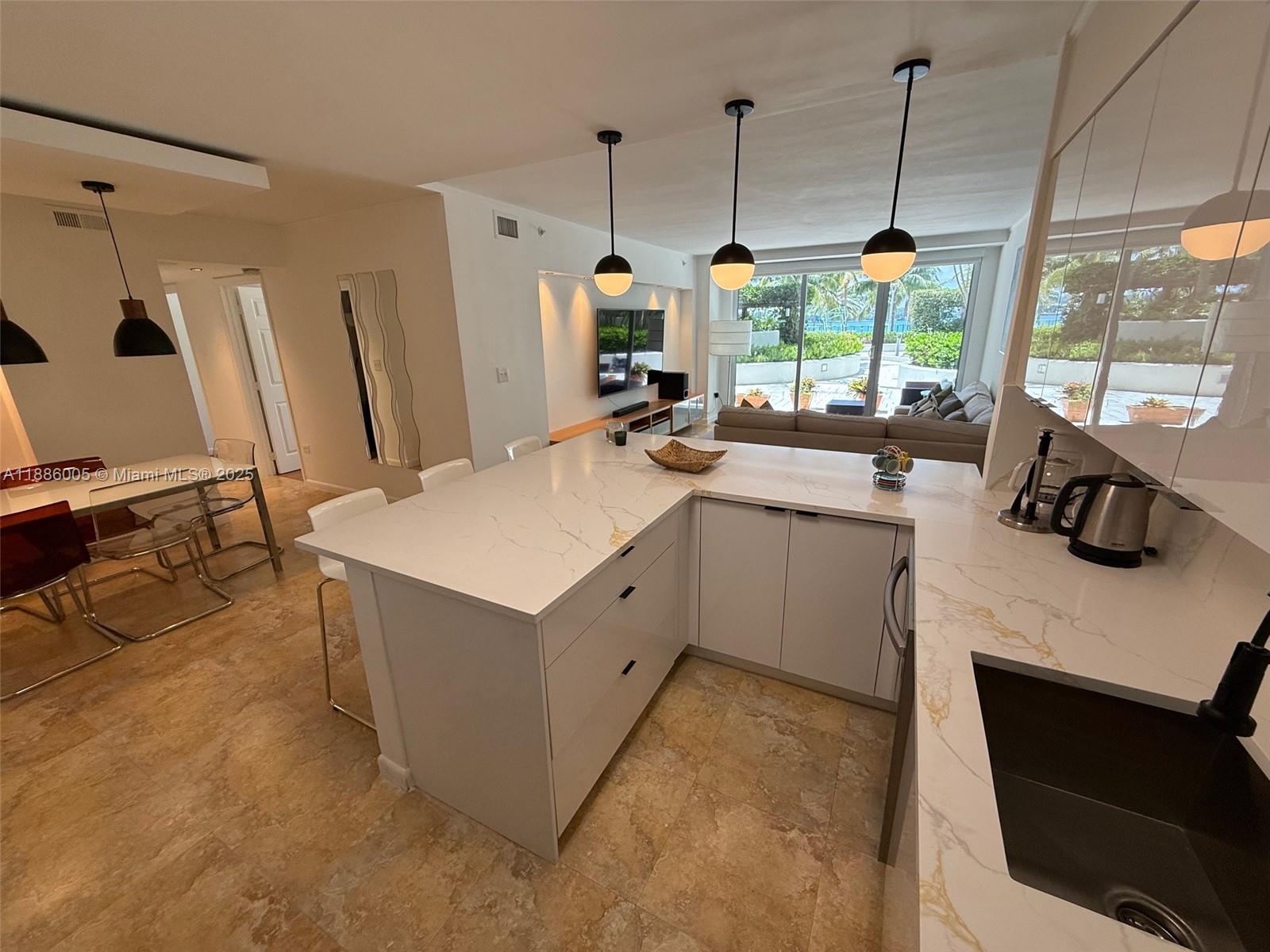 1500 Bay Road, Unit 122S Miami Beach, FL 33139 - Photo 10 of 44 a kitchen with a stove a sink a kitchen island a stove and a window