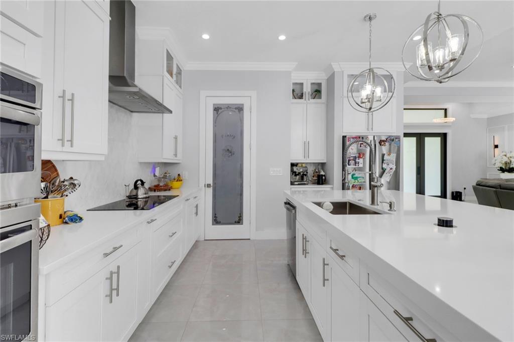 1086 21st Street Southwest Naples, FL 34117 - Photo 12 of 50 a large white kitchen with stainless steel appliances a stove oven a sink dishwasher and a refrigerator with wooden floor