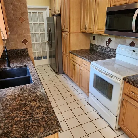 a kitchen with stainless steel appliances granite countertop a stove a sink and a microwave