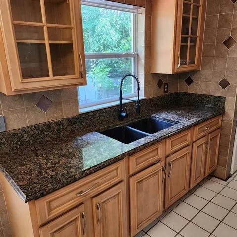 a kitchen with granite countertop a sink a stove and cabinets