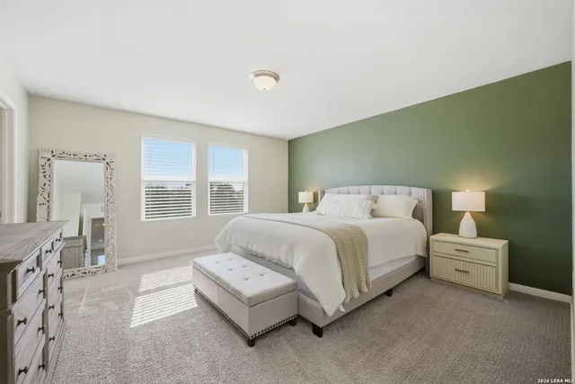 a spacious bedroom with a bed a table and windows