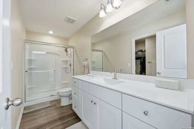 a bathroom with a toilet a sink a mirror and a shower