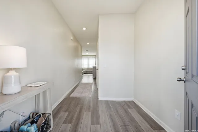 a view of a hallway with wooden floor and a bathroom