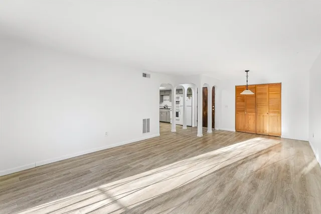 a view of empty room with wooden floor and fan