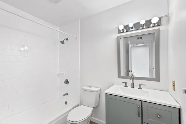 a bathroom with a toilet a sink a mirror a shower a vanity and mirror