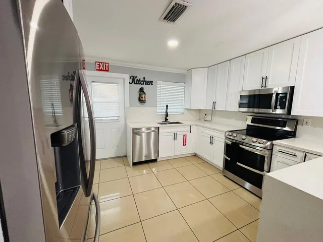 a kitchen with stainless steel appliances a refrigerator sink and microwave