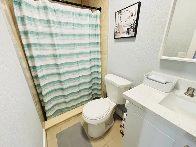 a white toilet sitting next to a bathroom sink and a mirror