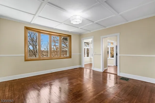 a view of an empty room with window and wooden floor