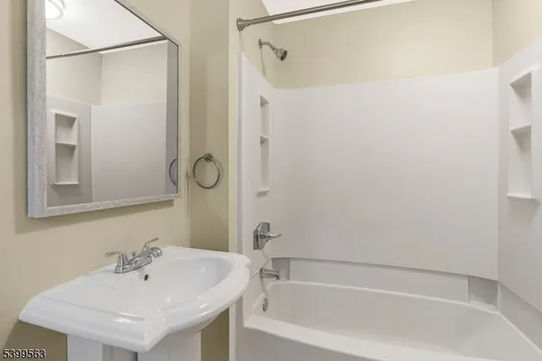 a white bath tub sitting next to a white sink and a mirror