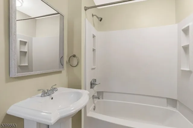 a white bath tub sitting next to a white sink and a mirror