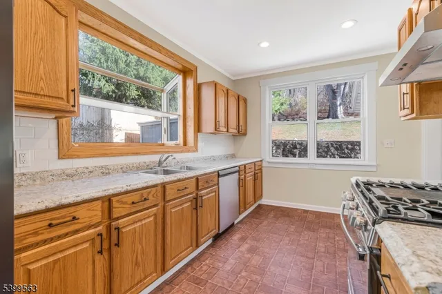 a kitchen with granite countertop a stove a sink and a wooden cabinets