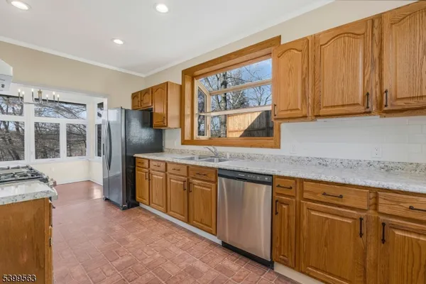 a kitchen with granite countertop wooden cabinets a stove a sink and a refrigerator