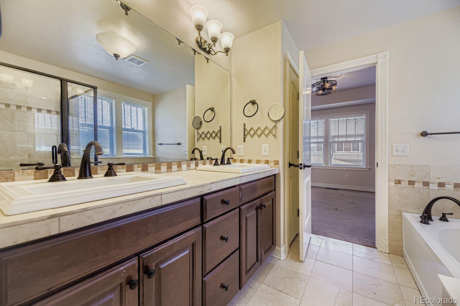 4927 South Addison Way Aurora, CO 80016 - Photo 16 of 24 a spacious bathroom with a tub sink and mirror