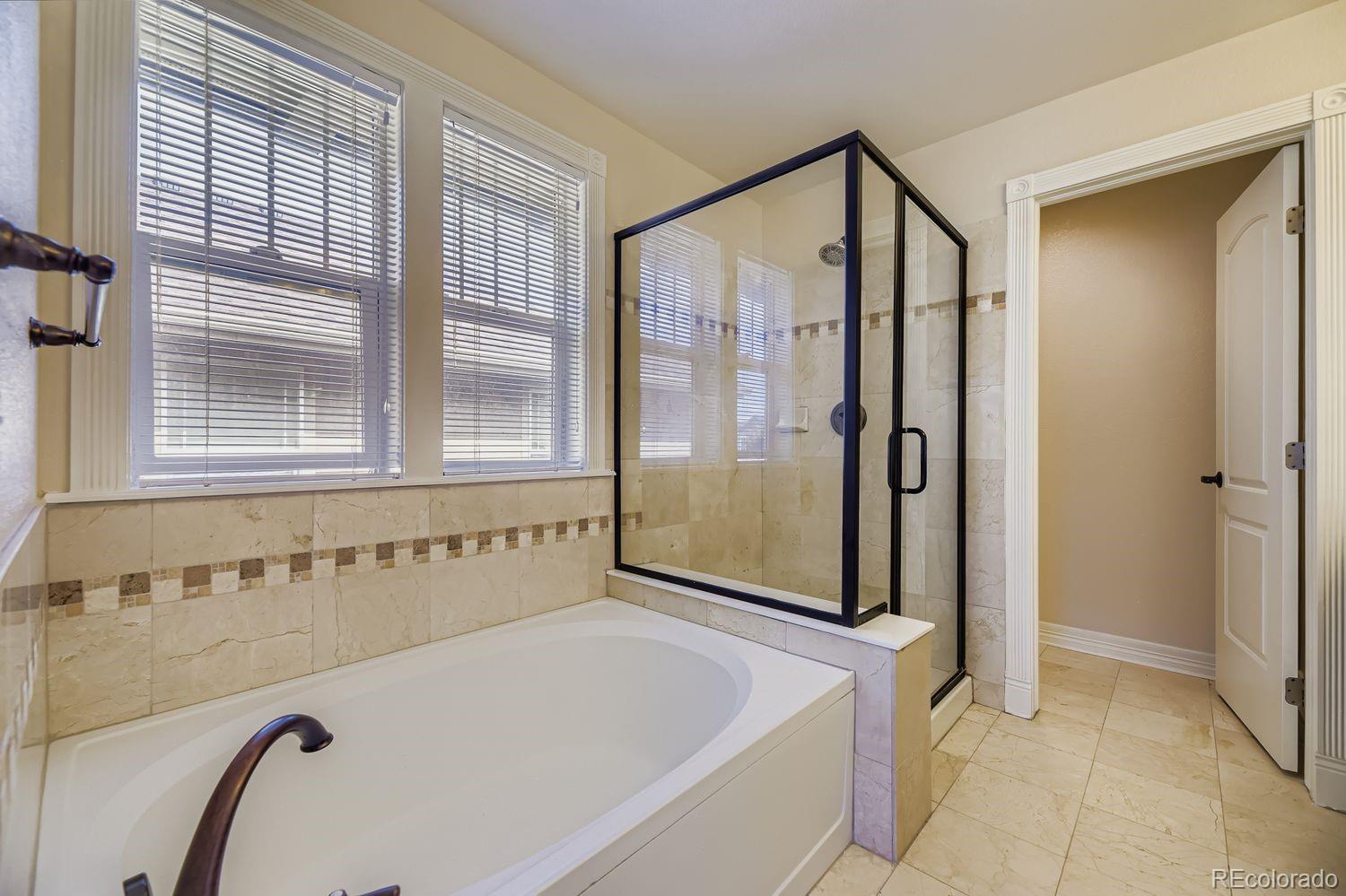 4927 South Addison Way Aurora, CO 80016 - Photo 17 of 24 a bathroom with a bathtub and a shower