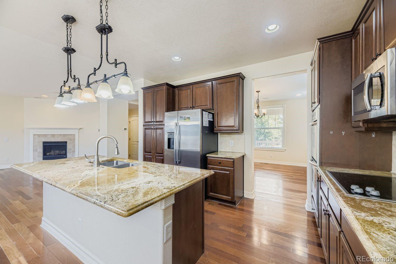 4927 South Addison Way Aurora, CO 80016 - Photo 5 of 24 a kitchen with stainless steel appliances granite countertop a kitchen island a stove a refrigerator a oven a sink and a center island