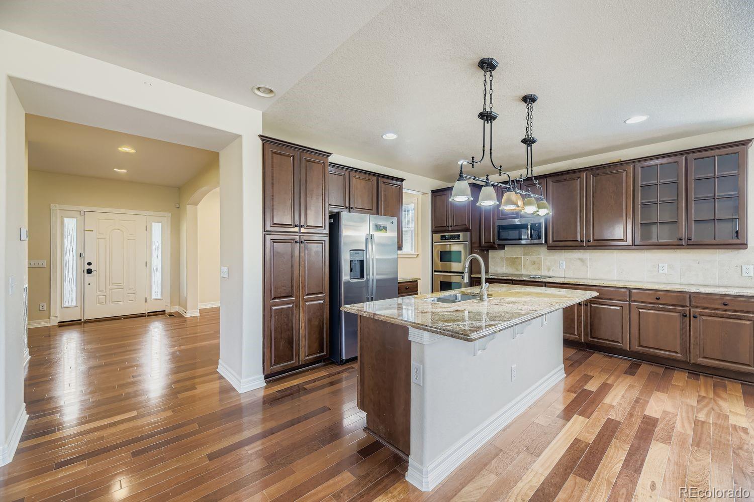 4927 South Addison Way Aurora, CO 80016 - Photo 7 of 24 a kitchen with stainless steel appliances granite countertop a sink refrigerator and cabinets