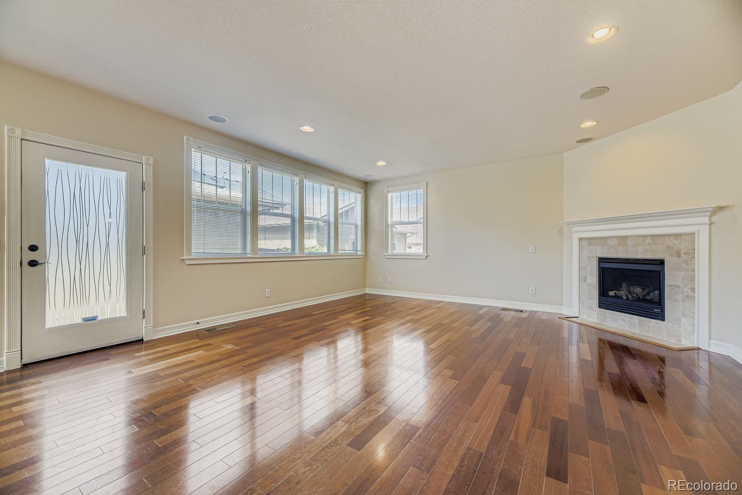 4927 South Addison Way Aurora, CO 80016 - Photo 9 of 24 an empty room with wooden floor fireplace and windows