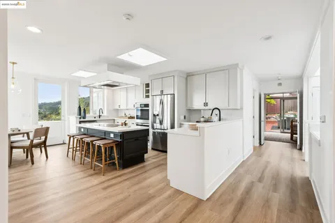 a kitchen with a stove a sink dishwasher a refrigerator and a dining table with wooden floor