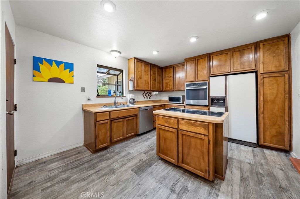 2976 Rancho Vista Drive Lucerne, CA 95458 - Photo 5 of 51 a kitchen with stainless steel appliances granite countertop a refrigerator a sink dishwasher and wooden cabinets with wooden floor