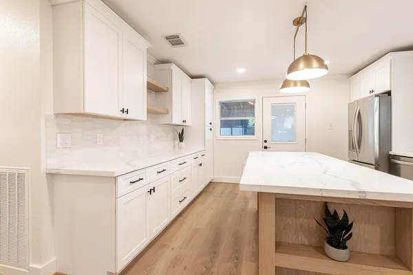a kitchen with kitchen island a stove a sink dishwasher and a refrigerator with wooden floor