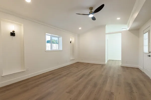 an empty room with wooden floor ceiling fan and windows