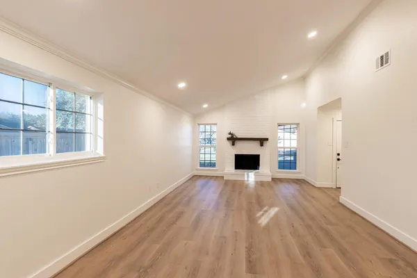 a view of empty room with wooden floor and fireplace