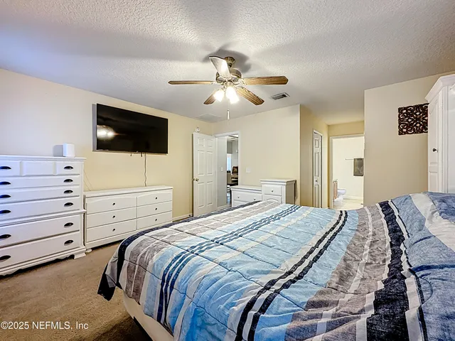 a bedroom with a bed a flat screen tv and a chandelier