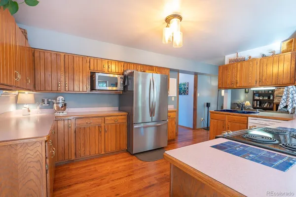 a kitchen with stainless steel appliances granite countertop a refrigerator a sink dishwasher a stove and a dining table with wooden floor