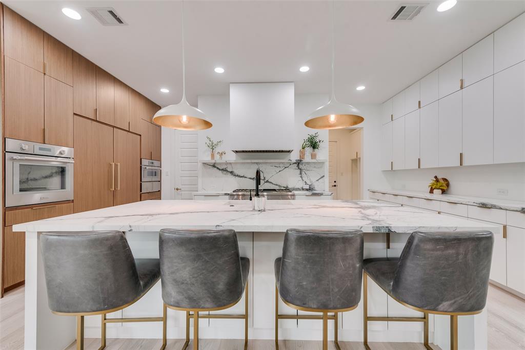 6443 Kenwood Avenue Dallas, TX 75214 - Photo 8 of 21 Kitchen featuring stainless steel oven, ventilation hood, a kitchen breakfast bar, light stone countertops, and recessed lighting