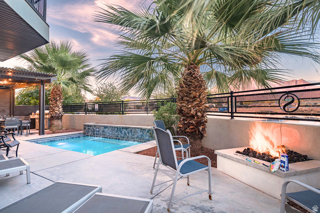 Outdoor living space featuring a built-in fire pit, a compact pool with a waterfall feature, and an adjacent covered patio area