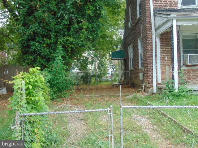 a backyard of a house with plants and large trees