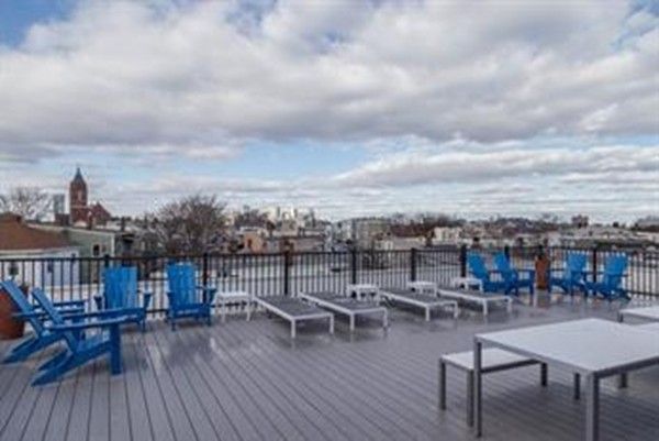 a view of a rooftop deck with chairs and wooden floor