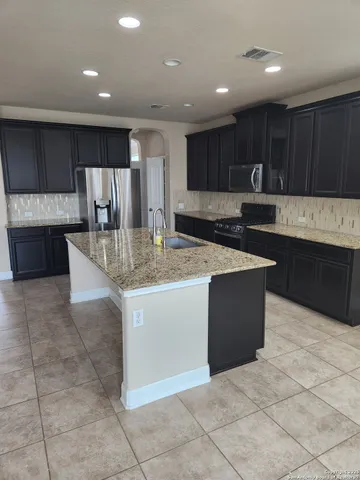 a kitchen with kitchen island granite countertop wooden cabinets and a sink