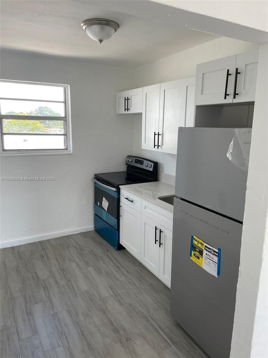 1261 Northwest 59th Street, Unit 5 Miami, FL 33142 - Photo 2 of 6 a kitchen with sink a refrigerator and a stove top oven