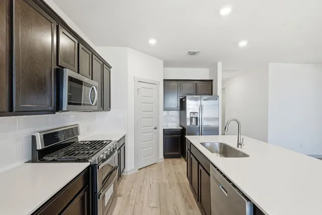 a view of kitchen with microwave oven stove and white cabinets with wooden floor