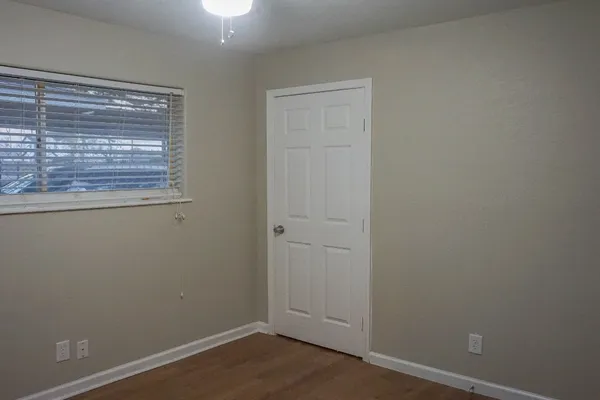 a view of an empty room with wooden floor and a window