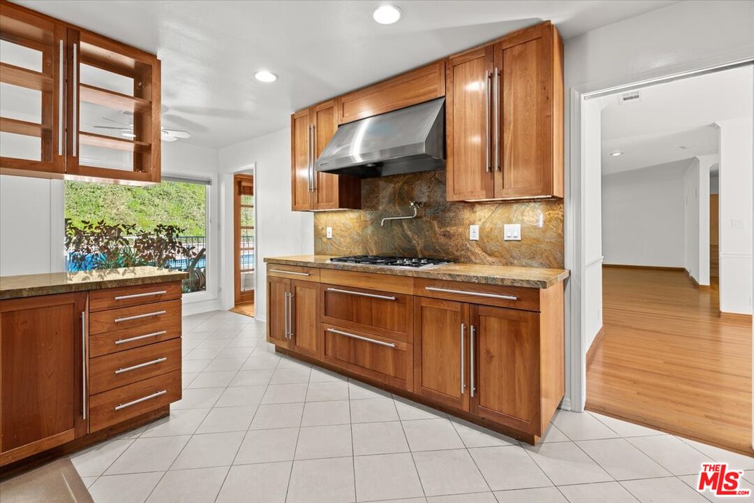 13521 Bayliss Road Los Angeles, CA 90049 - Photo 3 of 46 a kitchen with stainless steel appliances granite countertop a stove a sink and a microwave