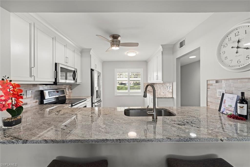 a kitchen with kitchen island granite countertop a sink a counter top space cabinets and stainless steel appliances