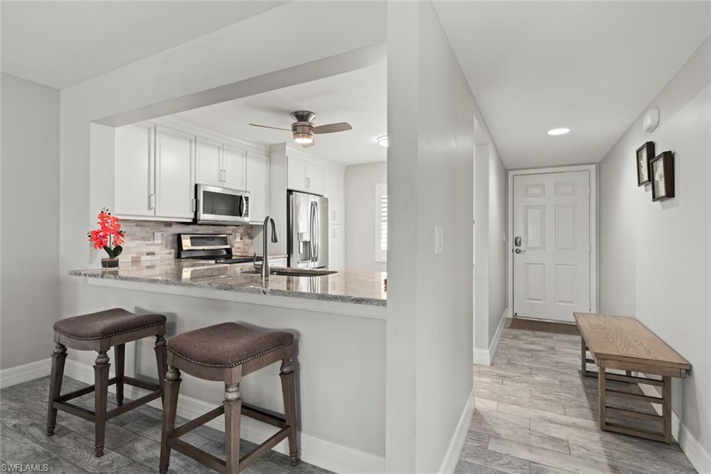 5965 Bloomfield Circle, Unit B104 Naples, FL 34112 - Photo 14 of 39 a kitchen with kitchen island a counter space a sink appliances and cabinets